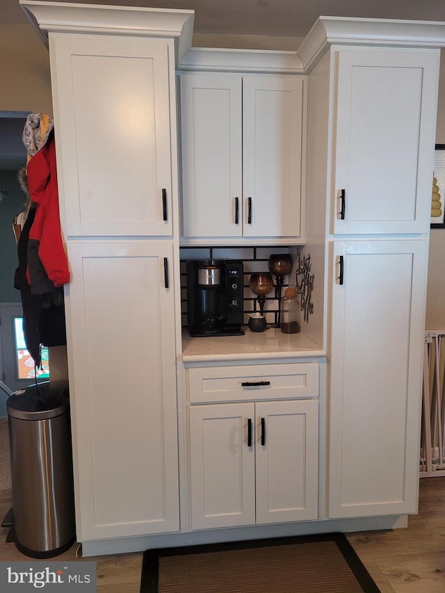 bar with white cabinetry and light hardwood / wood-style flooring