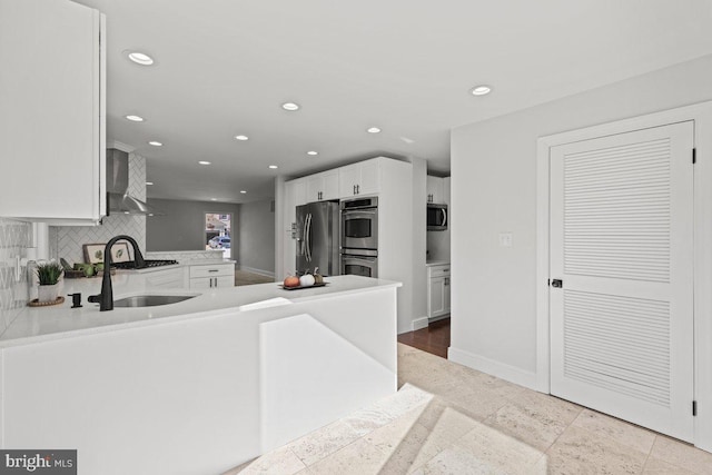 kitchen with stainless steel appliances, white cabinetry, wall chimney range hood, and backsplash