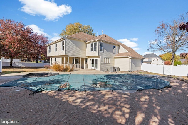 back of property featuring cooling unit, a covered pool, and a patio