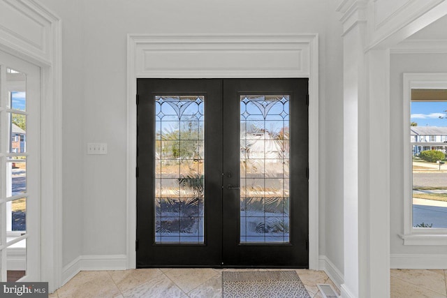 entrance foyer with crown molding and french doors