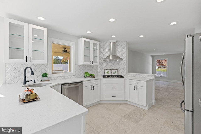 kitchen featuring tasteful backsplash, appliances with stainless steel finishes, sink, and wall chimney range hood