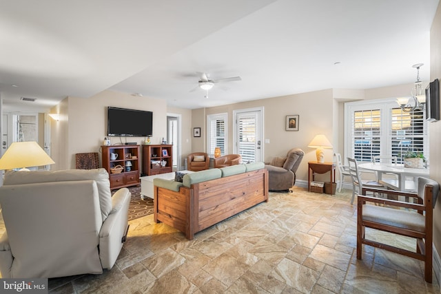 living room with plenty of natural light and ceiling fan with notable chandelier