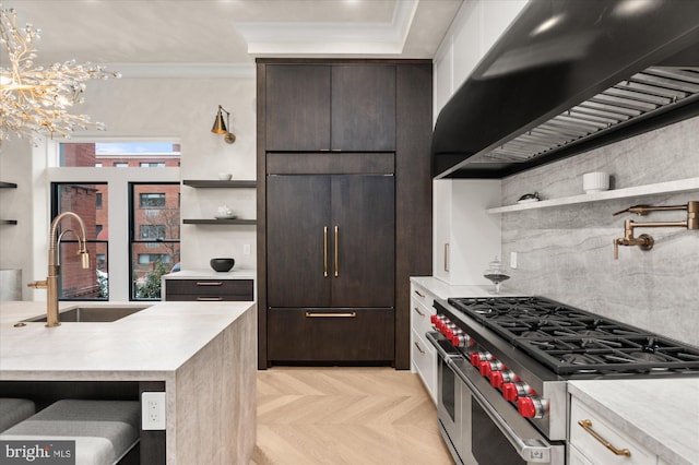 kitchen with sink, light parquet floors, dark brown cabinetry, premium appliances, and ornamental molding