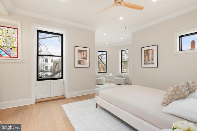 bedroom featuring multiple windows, crown molding, and light wood-type flooring