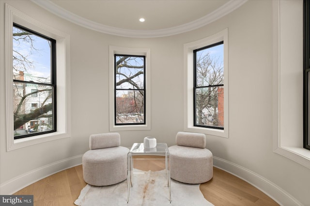 living area with hardwood / wood-style flooring and crown molding