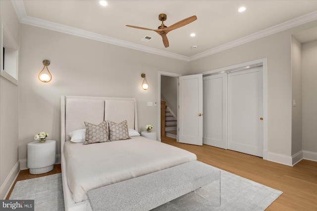 bedroom featuring crown molding, hardwood / wood-style floors, ceiling fan, and a closet