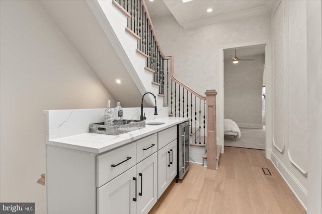 bathroom with wine cooler, hardwood / wood-style flooring, vanity, ceiling fan, and crown molding