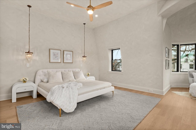 bedroom featuring hardwood / wood-style flooring, ceiling fan, and a high ceiling