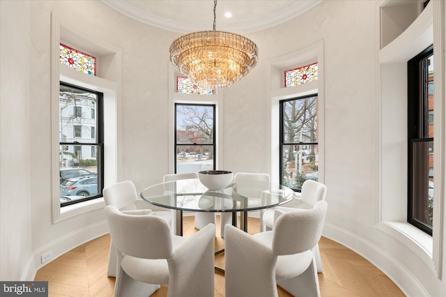 dining room with light parquet floors, crown molding, and a notable chandelier