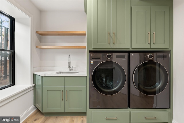 laundry room featuring cabinets, independent washer and dryer, sink, and light hardwood / wood-style flooring