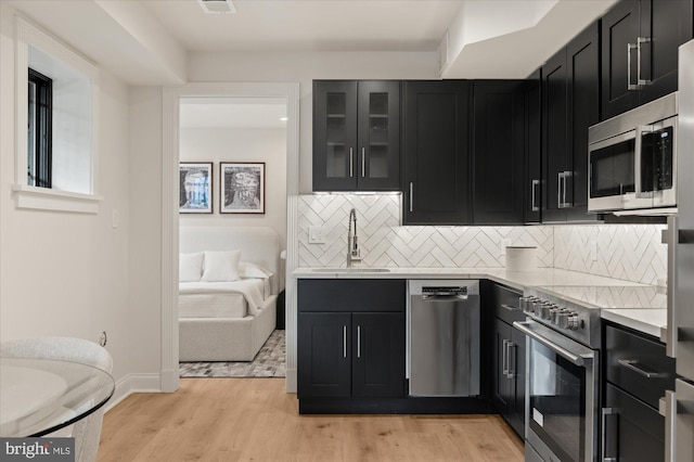 kitchen featuring stainless steel appliances, tasteful backsplash, sink, and light hardwood / wood-style flooring