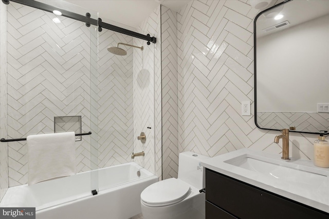 full bathroom featuring toilet, tile walls, vanity, enclosed tub / shower combo, and decorative backsplash