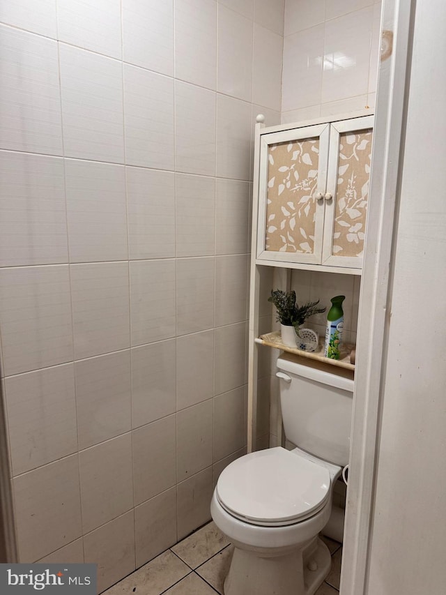 bathroom featuring toilet, tile patterned flooring, and tile walls