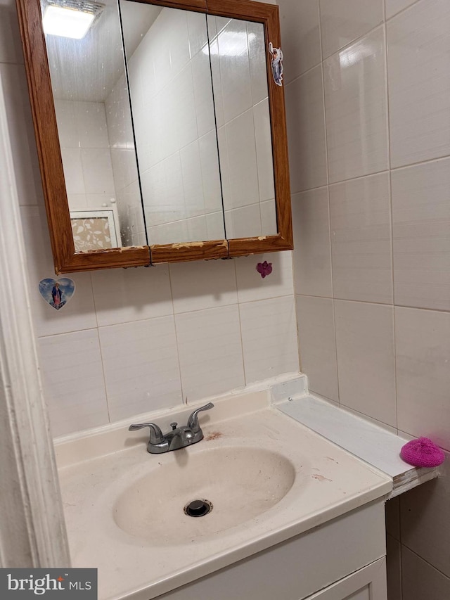 bathroom featuring vanity and tile walls