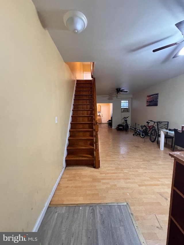 stairs featuring hardwood / wood-style flooring and ceiling fan