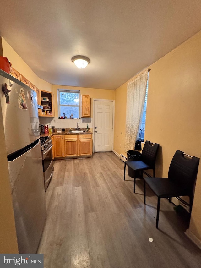 kitchen featuring stainless steel appliances, sink, light hardwood / wood-style floors, and a baseboard heating unit