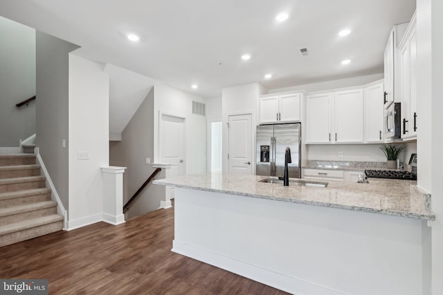 kitchen with sink, white cabinetry, appliances with stainless steel finishes, kitchen peninsula, and light stone countertops