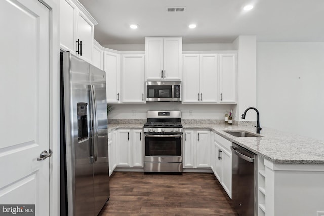 kitchen with stainless steel appliances, light stone countertops, sink, and white cabinets