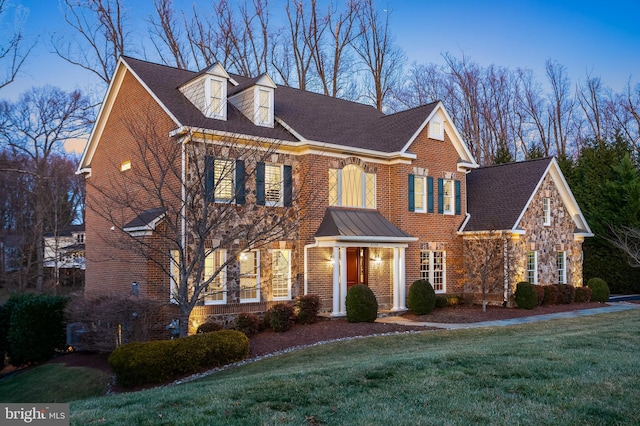 colonial inspired home featuring stone siding, a front lawn, and brick siding