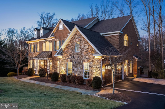 view of front of house with a garage, a front yard, stone siding, and driveway