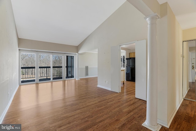 unfurnished living room featuring decorative columns, wood-type flooring, and high vaulted ceiling