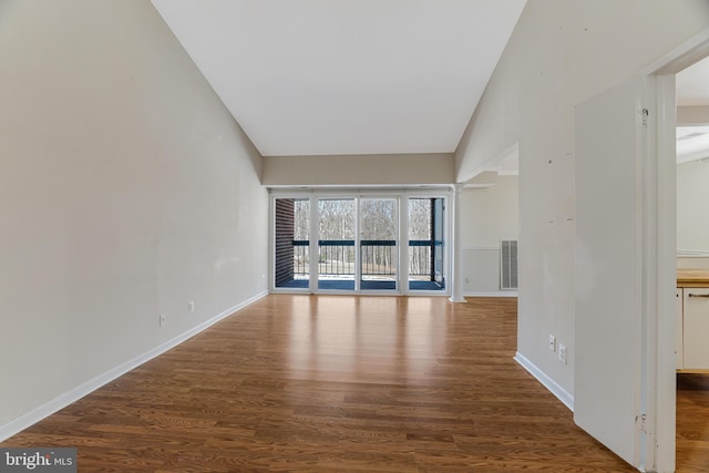 unfurnished living room with dark wood-type flooring and vaulted ceiling