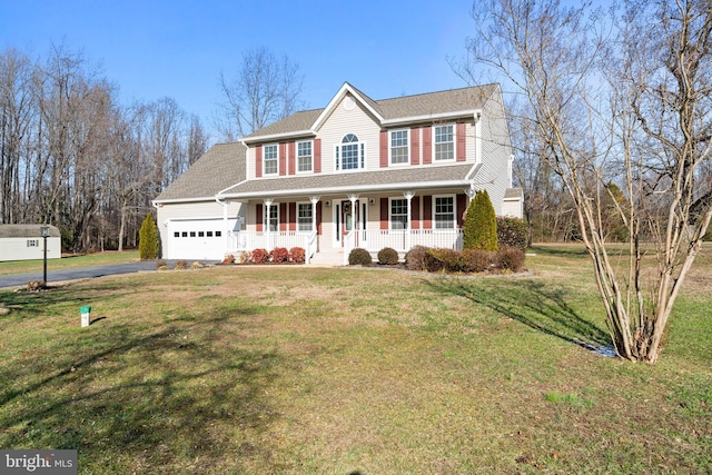 colonial home featuring a garage, a front yard, and covered porch