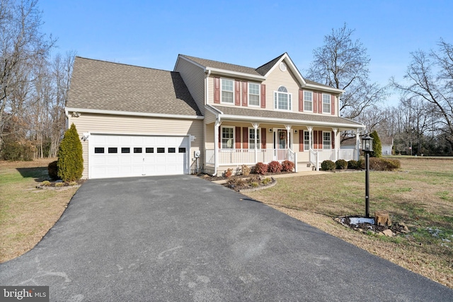 view of front of property with a porch, a garage, and a front lawn