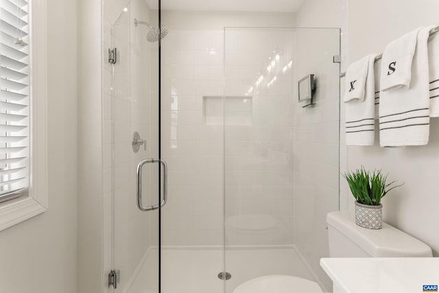 bathroom with a shower with shower door and toilet