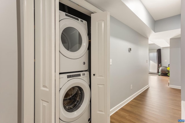 laundry area featuring stacked washer / drying machine and light hardwood / wood-style floors