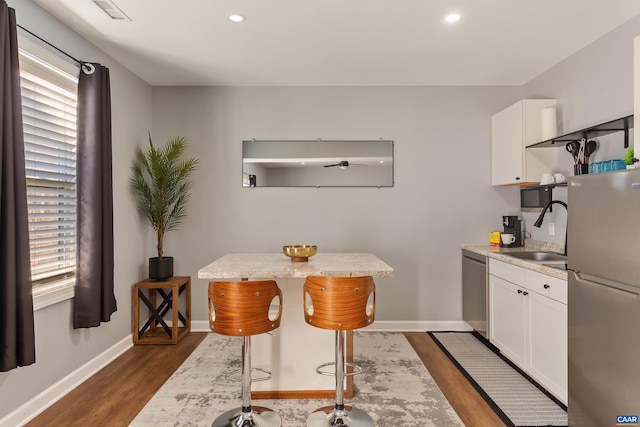 kitchen featuring white cabinetry, appliances with stainless steel finishes, a kitchen breakfast bar, and sink