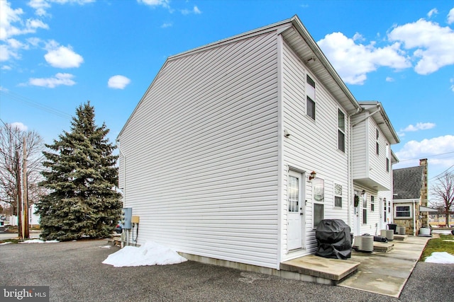 view of side of property with cooling unit and a patio area