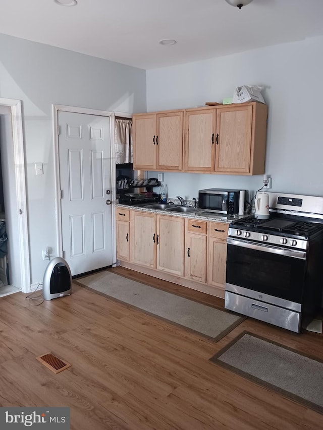 kitchen with sink, hardwood / wood-style flooring, stainless steel appliances, and light brown cabinets