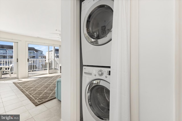 laundry room with stacked washer / dryer and light tile patterned floors