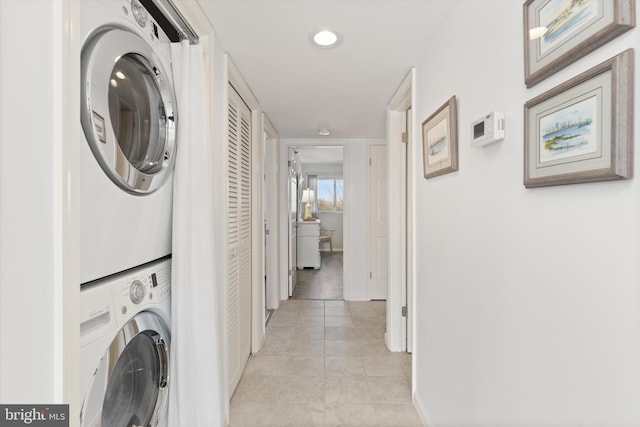 laundry room with stacked washing maching and dryer and light tile patterned floors