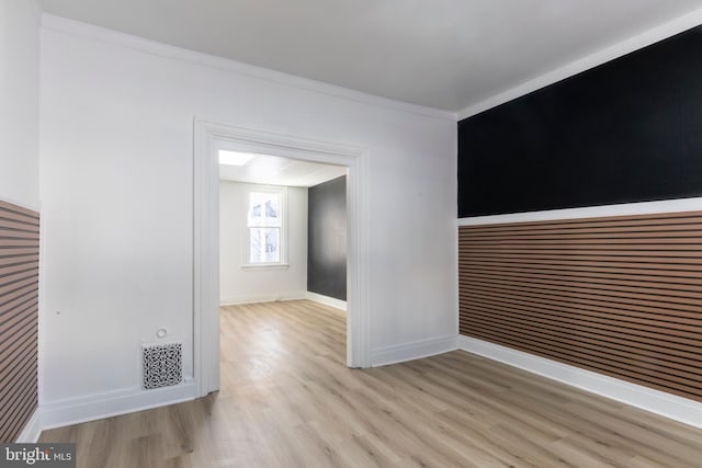 spare room featuring ornamental molding and light hardwood / wood-style floors