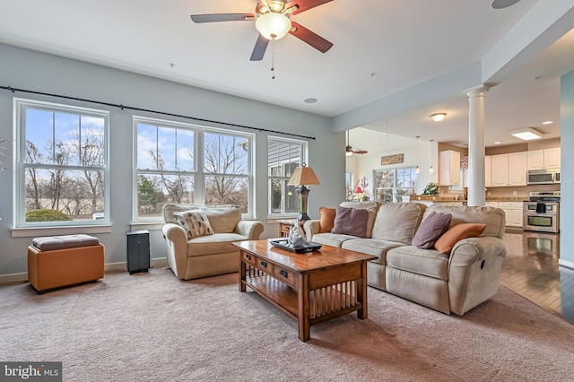 living room with decorative columns, light colored carpet, and ceiling fan