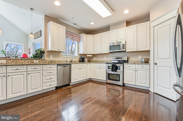 kitchen with appliances with stainless steel finishes, stone countertops, pendant lighting, and white cabinets