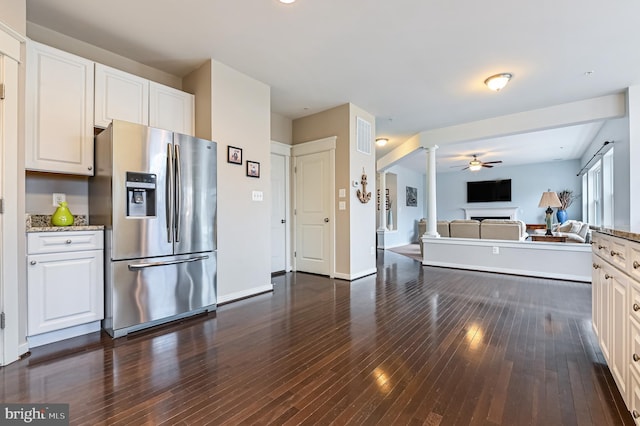 kitchen with stainless steel refrigerator with ice dispenser, white cabinetry, light stone counters, dark hardwood / wood-style flooring, and decorative columns