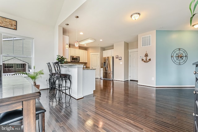 kitchen featuring appliances with stainless steel finishes, a kitchen bar, white cabinets, stone countertops, and kitchen peninsula