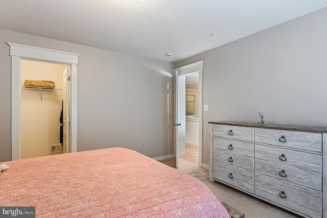 bedroom with a spacious closet, light carpet, and a closet