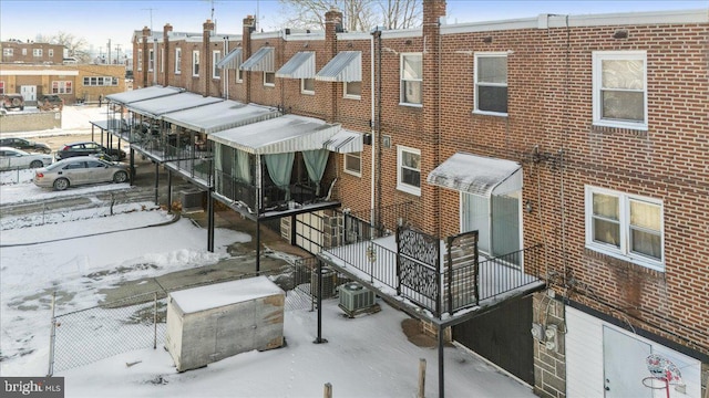 snow covered building featuring central AC unit