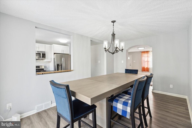 dining space featuring hardwood / wood-style flooring, a chandelier, and a textured ceiling