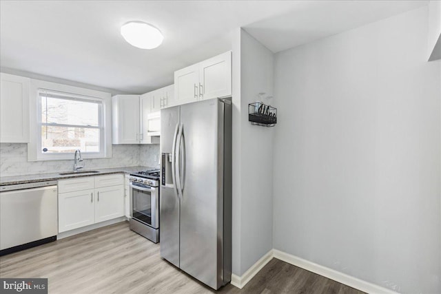 kitchen with backsplash, stainless steel appliances, sink, and white cabinets