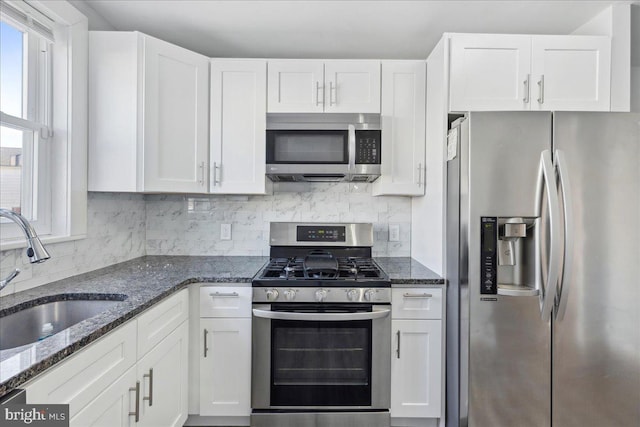 kitchen featuring sink, tasteful backsplash, appliances with stainless steel finishes, dark stone counters, and white cabinets