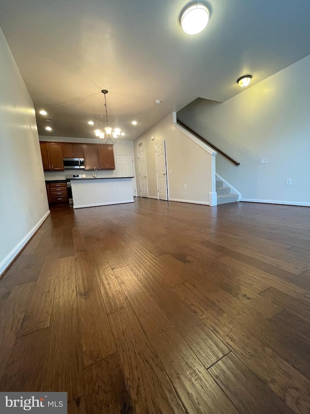 unfurnished living room with sink, dark hardwood / wood-style floors, and a chandelier