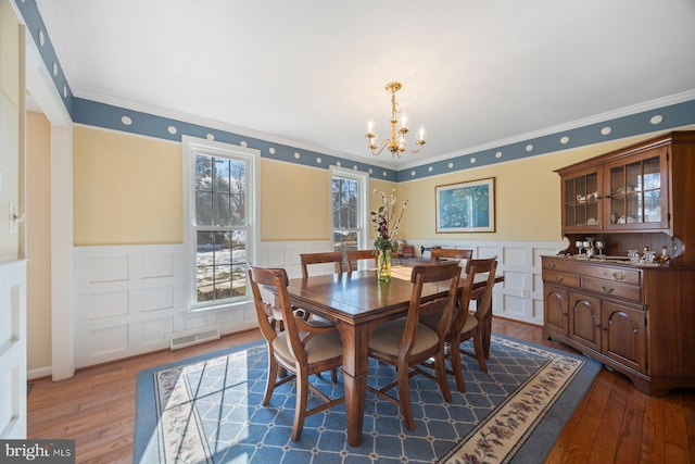 dining area with a notable chandelier, ornamental molding, and dark hardwood / wood-style floors