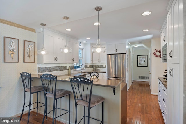 kitchen featuring pendant lighting, white cabinetry, a breakfast bar area, kitchen peninsula, and stainless steel appliances