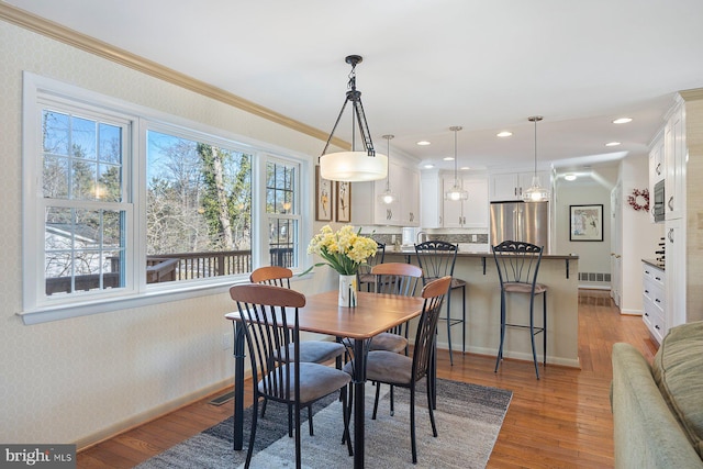 dining room featuring ornamental molding and light hardwood / wood-style flooring