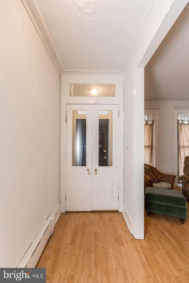 entryway with baseboard heating, french doors, a textured ceiling, and light wood-type flooring